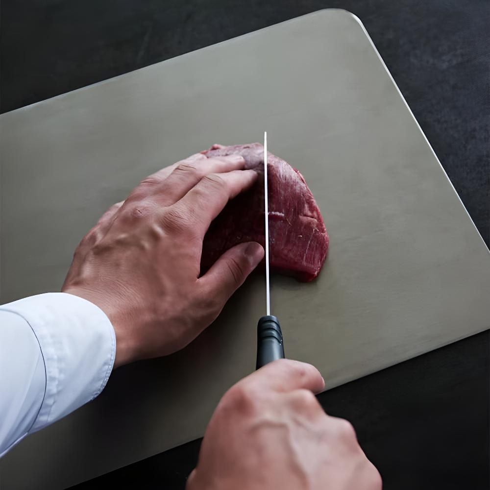 Slicing raw beef on the stainless steel cutting board