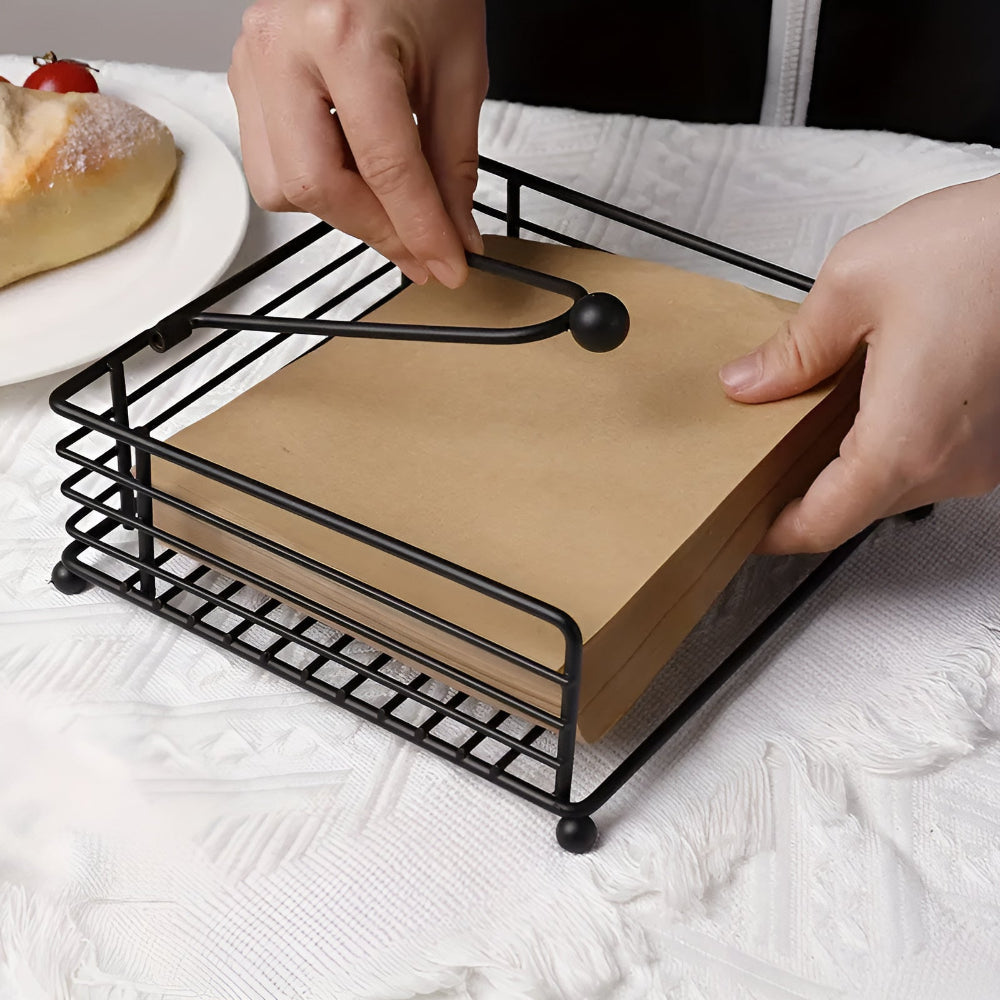 Black iron napkin holder with paper napkins on a table