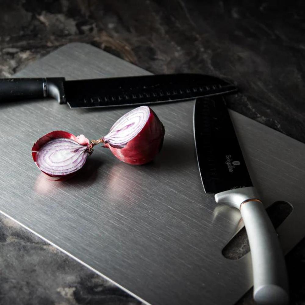 Red onion and knives on the stainless steel cutting board
