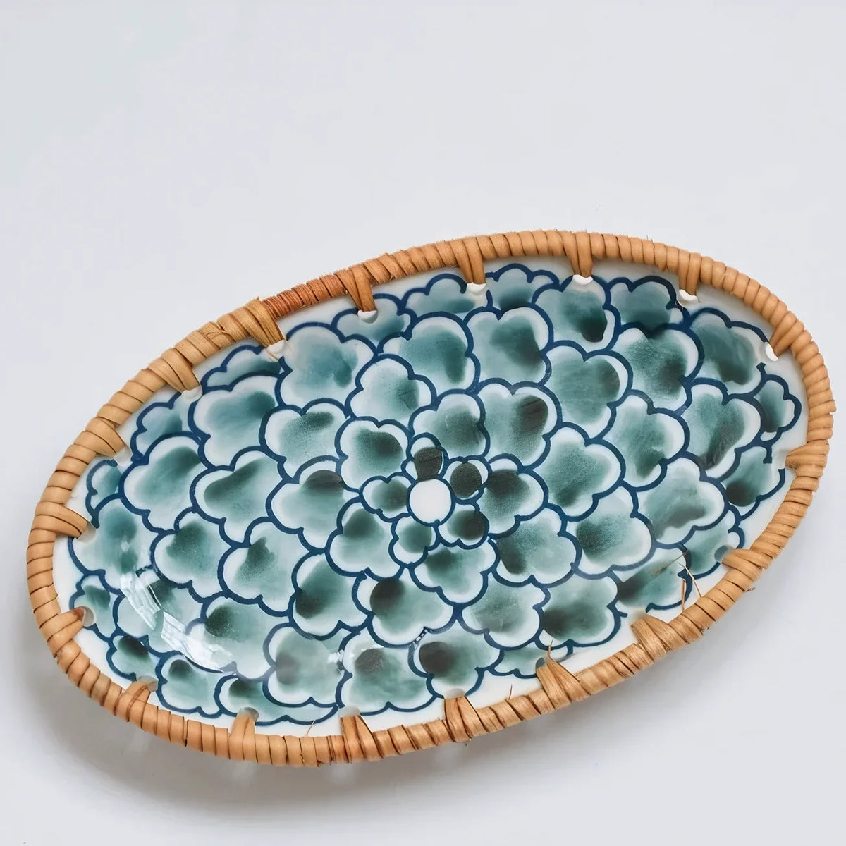 Oval ceramic serving plate with a dark green flower pattern and woven rim