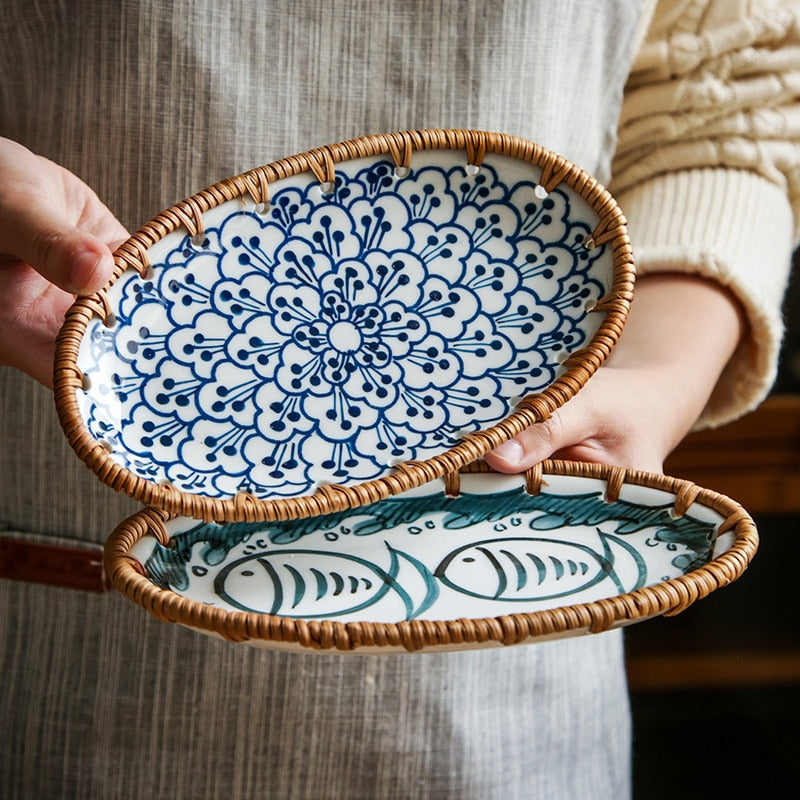 Hands holding two oval ceramic serving plates with woven rims