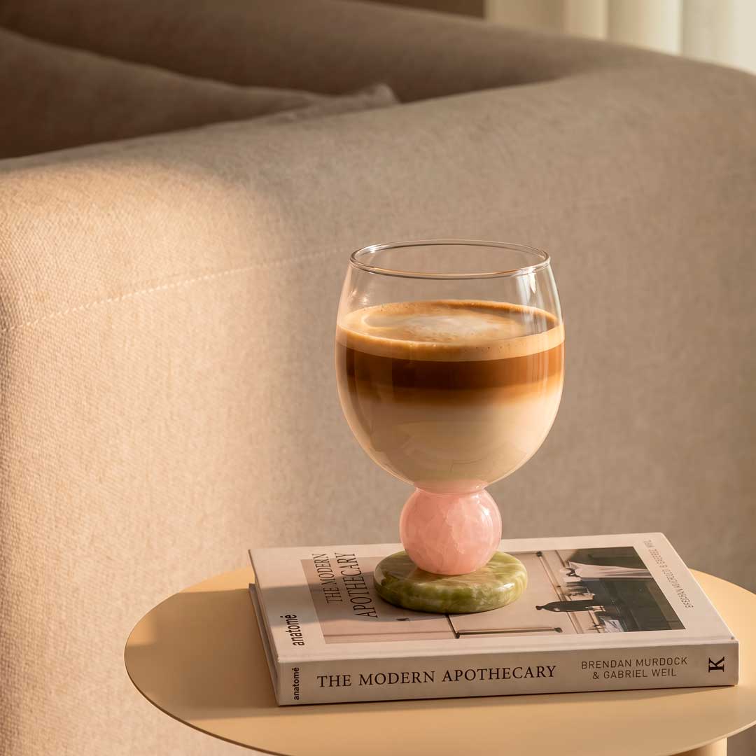 Stone base glass with an iced coffee on a stack of books