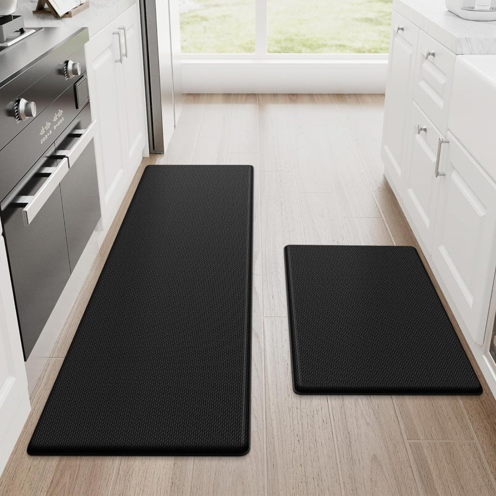 Two black anti-fatigue kitchen mats on a wood kitchen floor