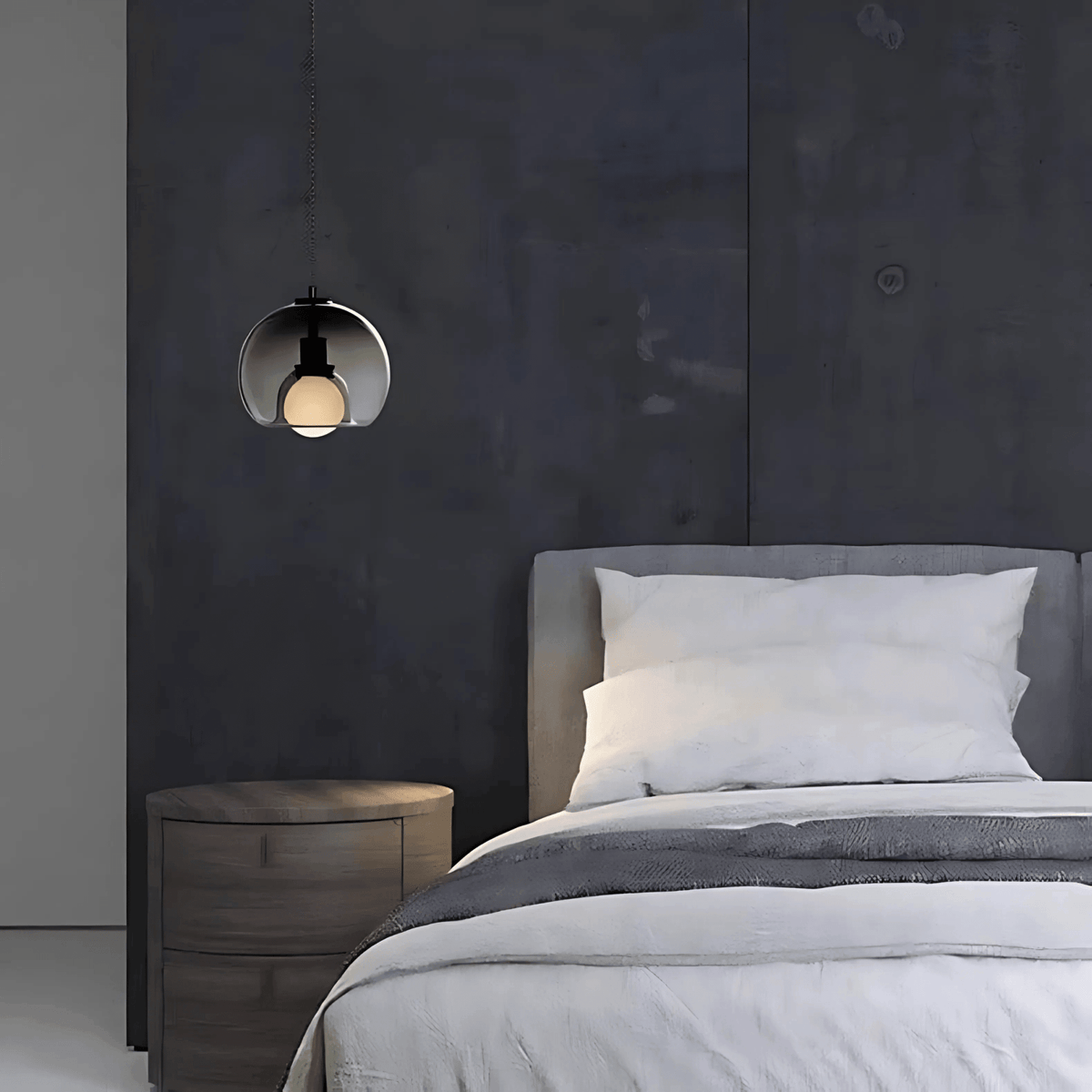 Smoke gray Clyde pendant light beside a bed