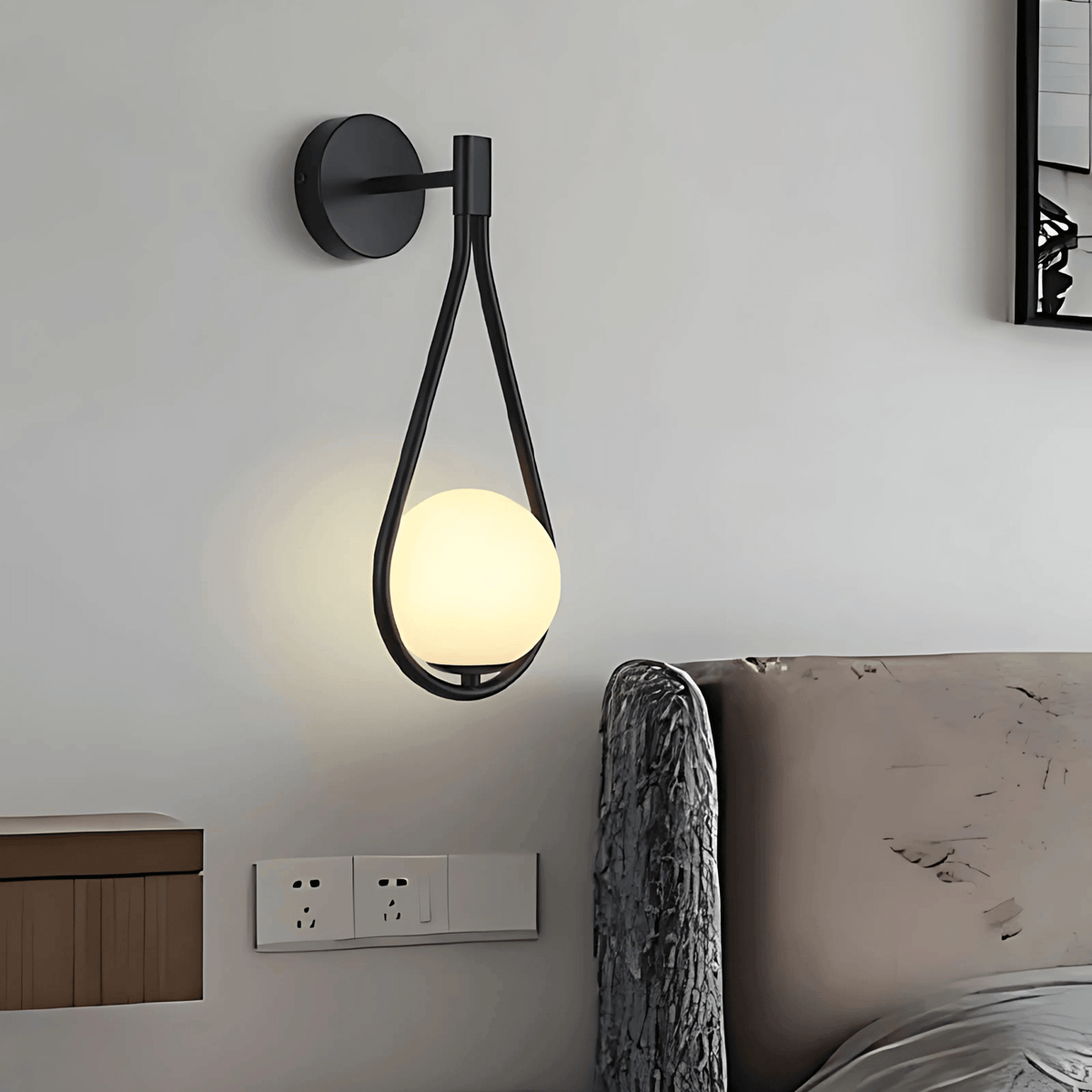 Black globe wall sconce on a white bedroom wall