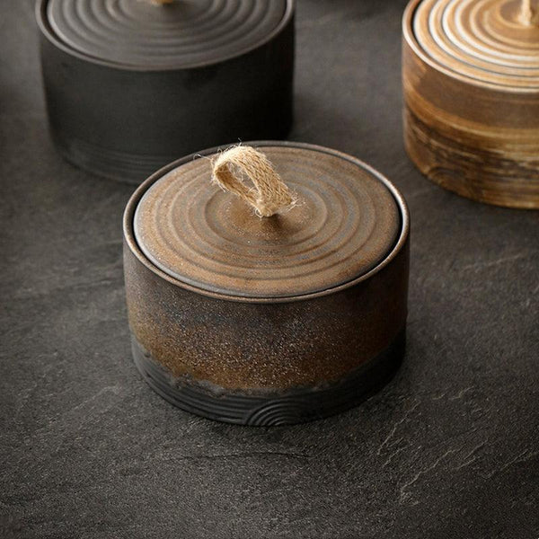 Handmade Japanese ceramic storage jar with hemp rope handle on a light styled tabletop