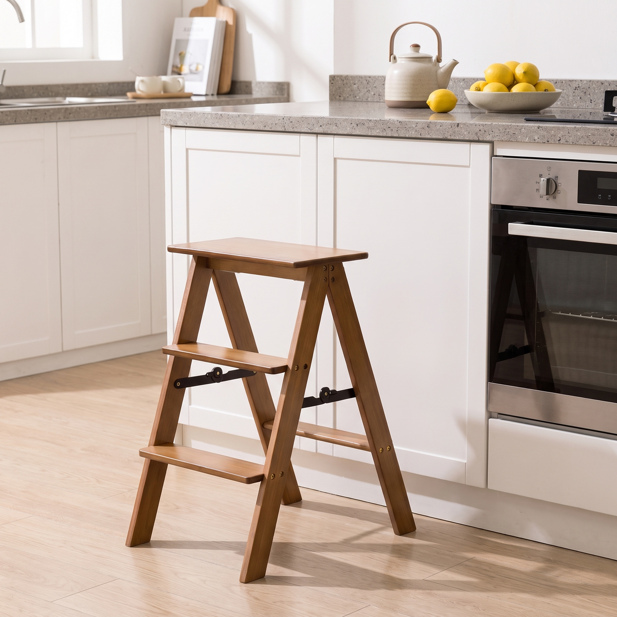 Bamboo step stool in front of white kitchen cabinets and an oven