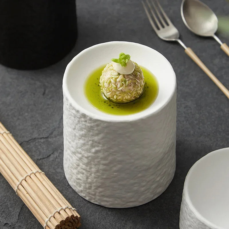 Tall white pedestal dish holding a starter on a dark slate surface