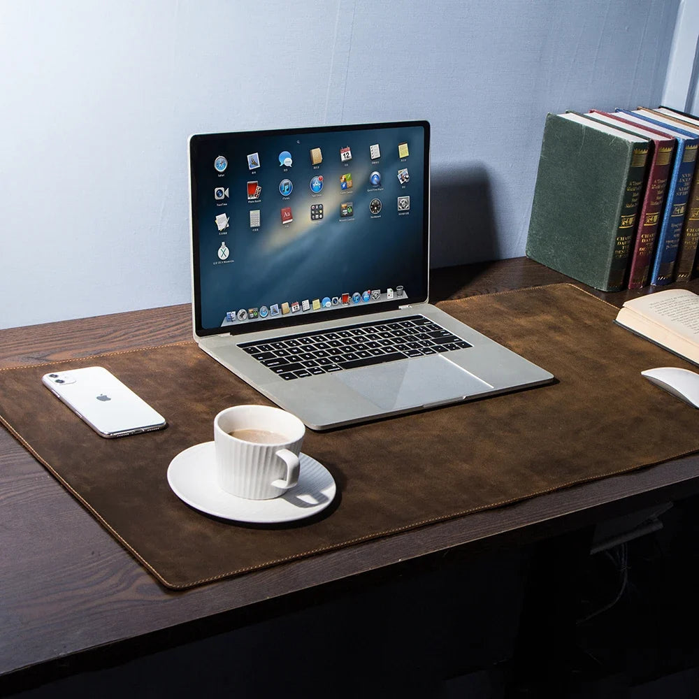 Brown leather desk mat under a laptop, phone and coffee cup on a desk
