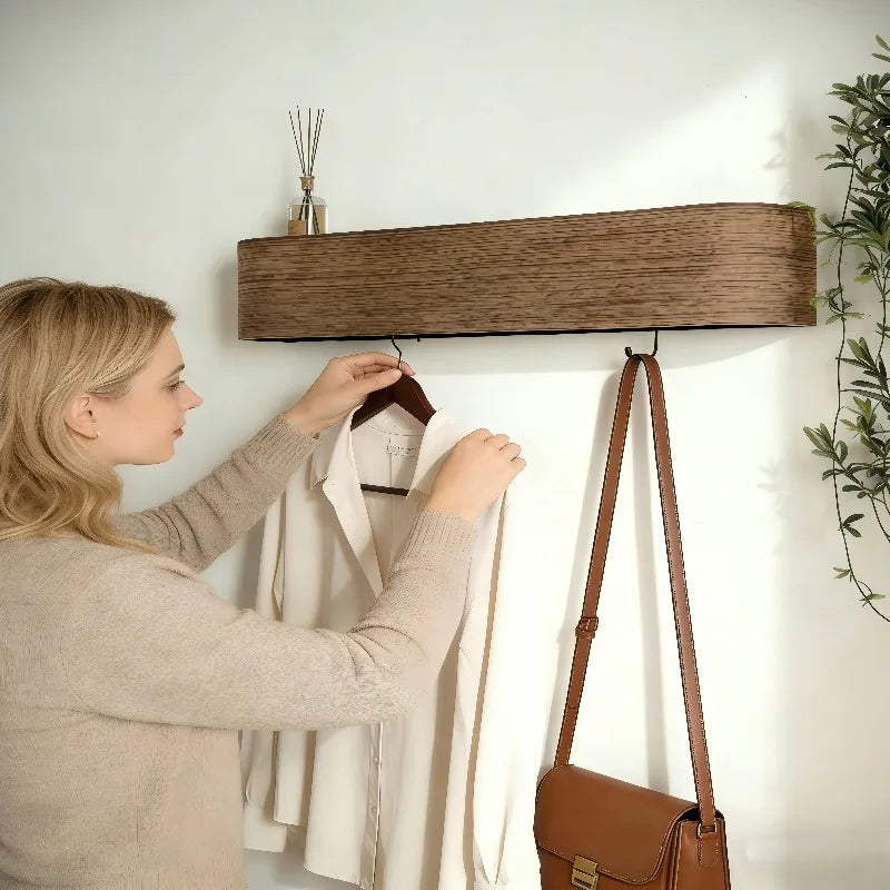 Woman hanging a jacket on the hooks under a curved wall shelf