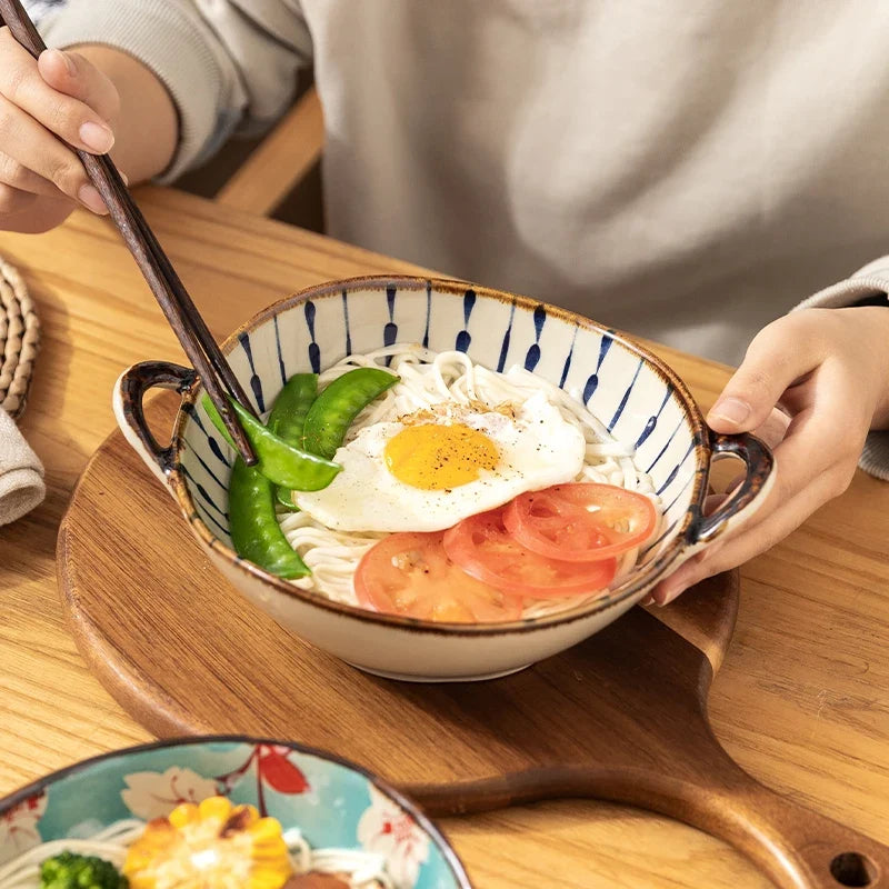 Hands holding a blue lines bowl with egg, tomato and peas
