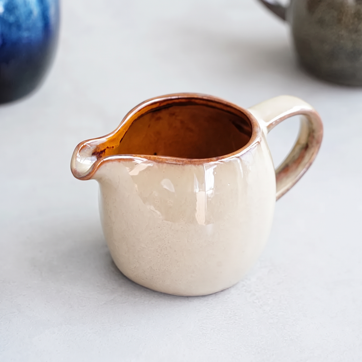 Cream glazed ceramic sauce jug with a pinched pouring lip