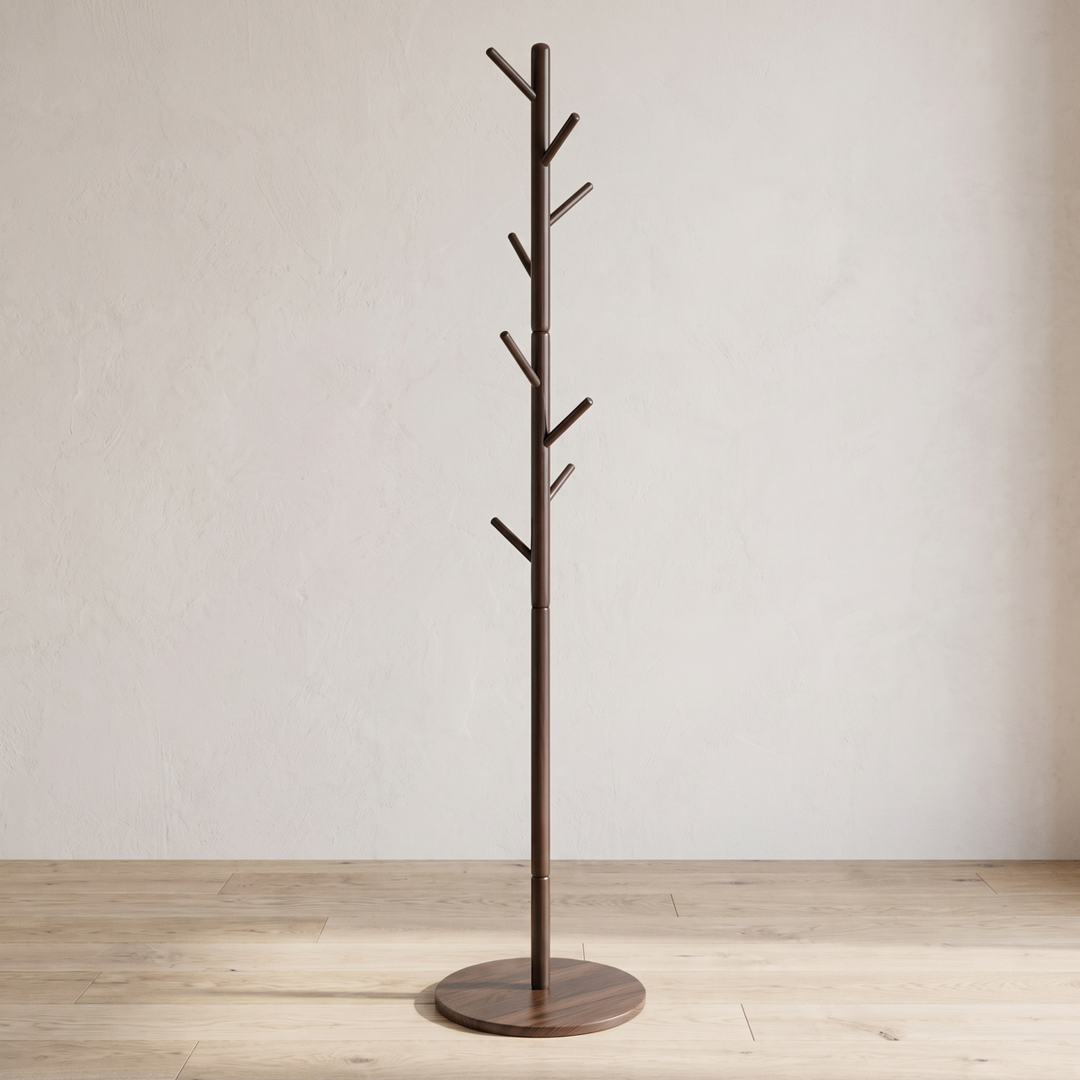 Dark brown wood coat stand with a round base against a white wall