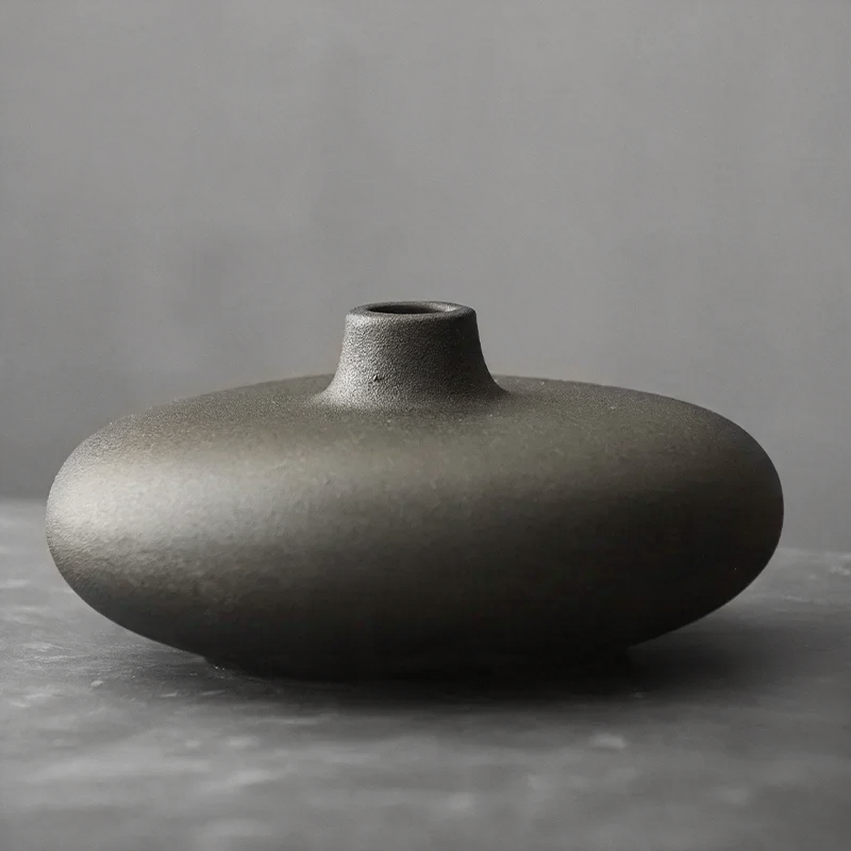 Low black ceramic pebble vase with a small neck