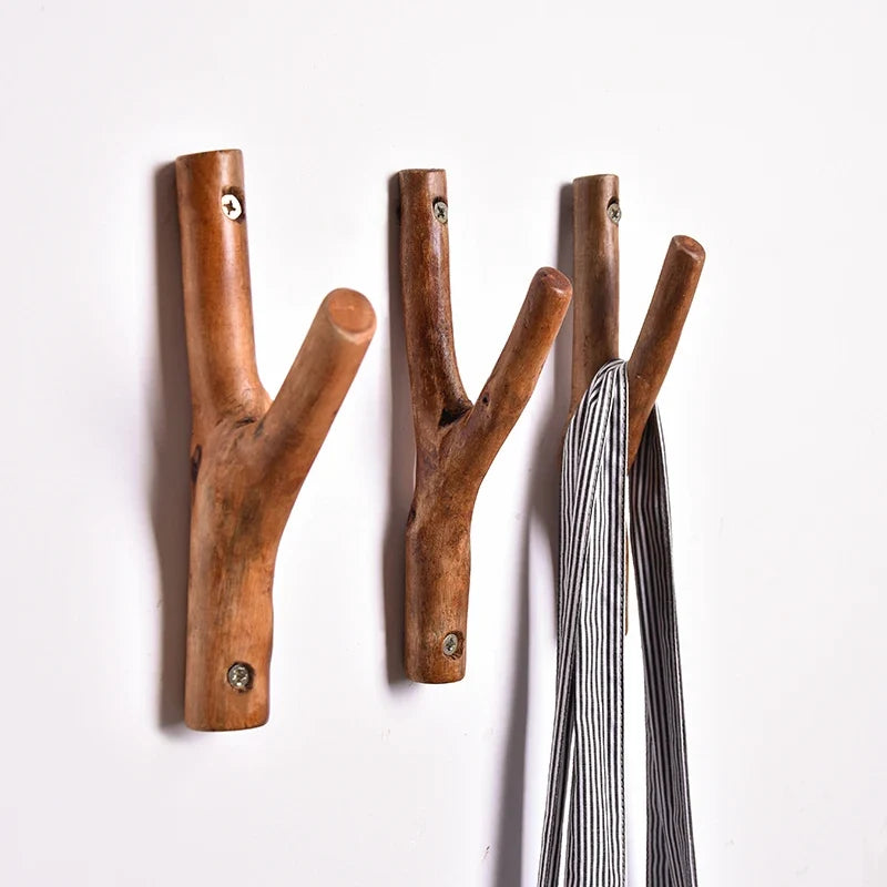 Branch wall hooks on a white wall with a striped cloth on one fork
