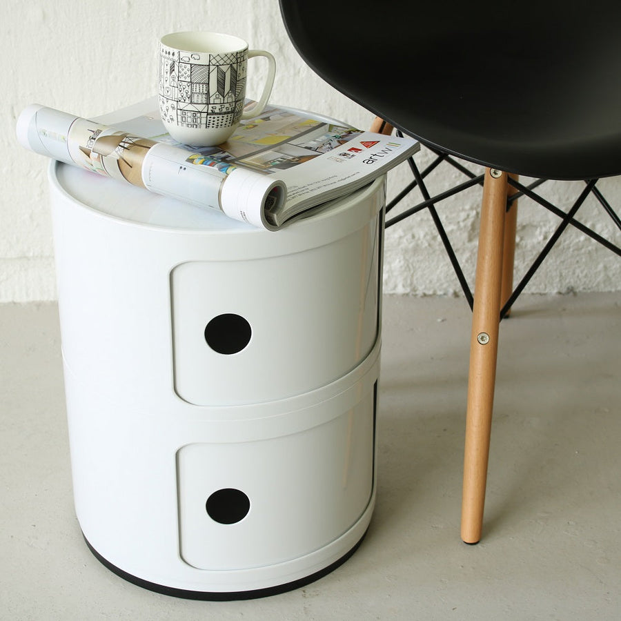 White two tier round storage unit used as a side table next to a chair