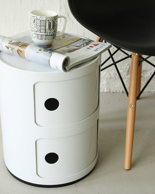 White two tier round storage unit used as a side table next to a chair