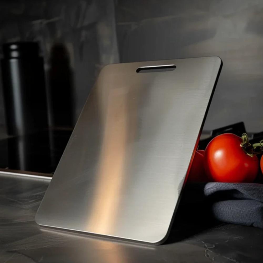 Stainless steel cutting board leaning on a dark kitchen counter