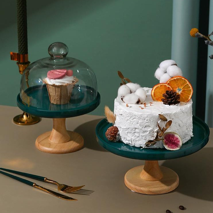 Green footed cake stands with glass domes on a table