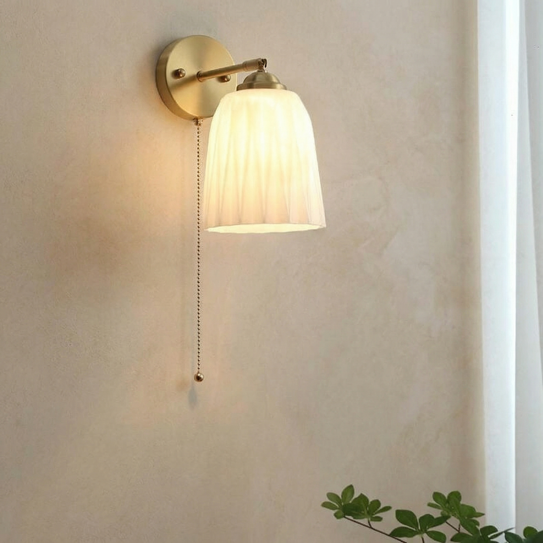 Milk glass wall sconce by Qonforta showing the diffused shade and curved brass detailing