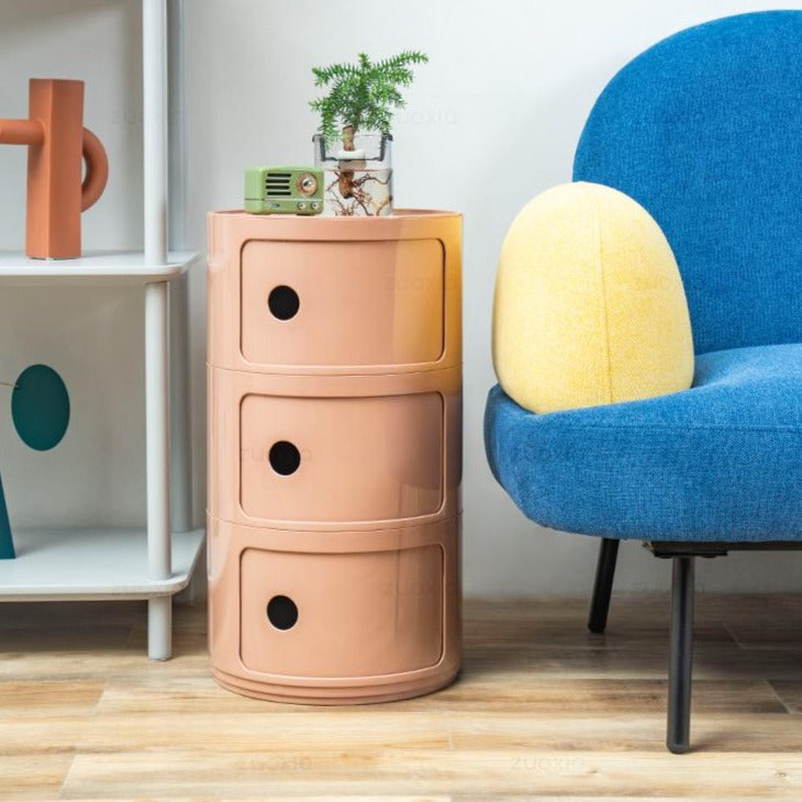 Nude three tier round storage unit next to a blue armchair