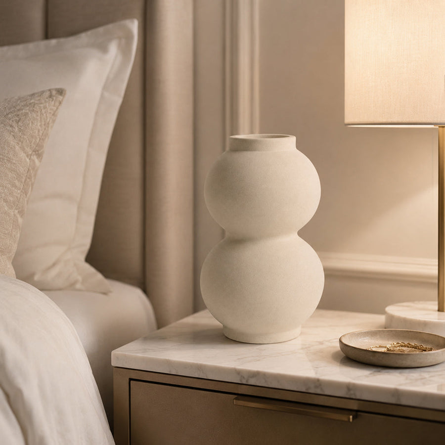 Plain matte unglazed ceramic vase holding dried stems in a living room
