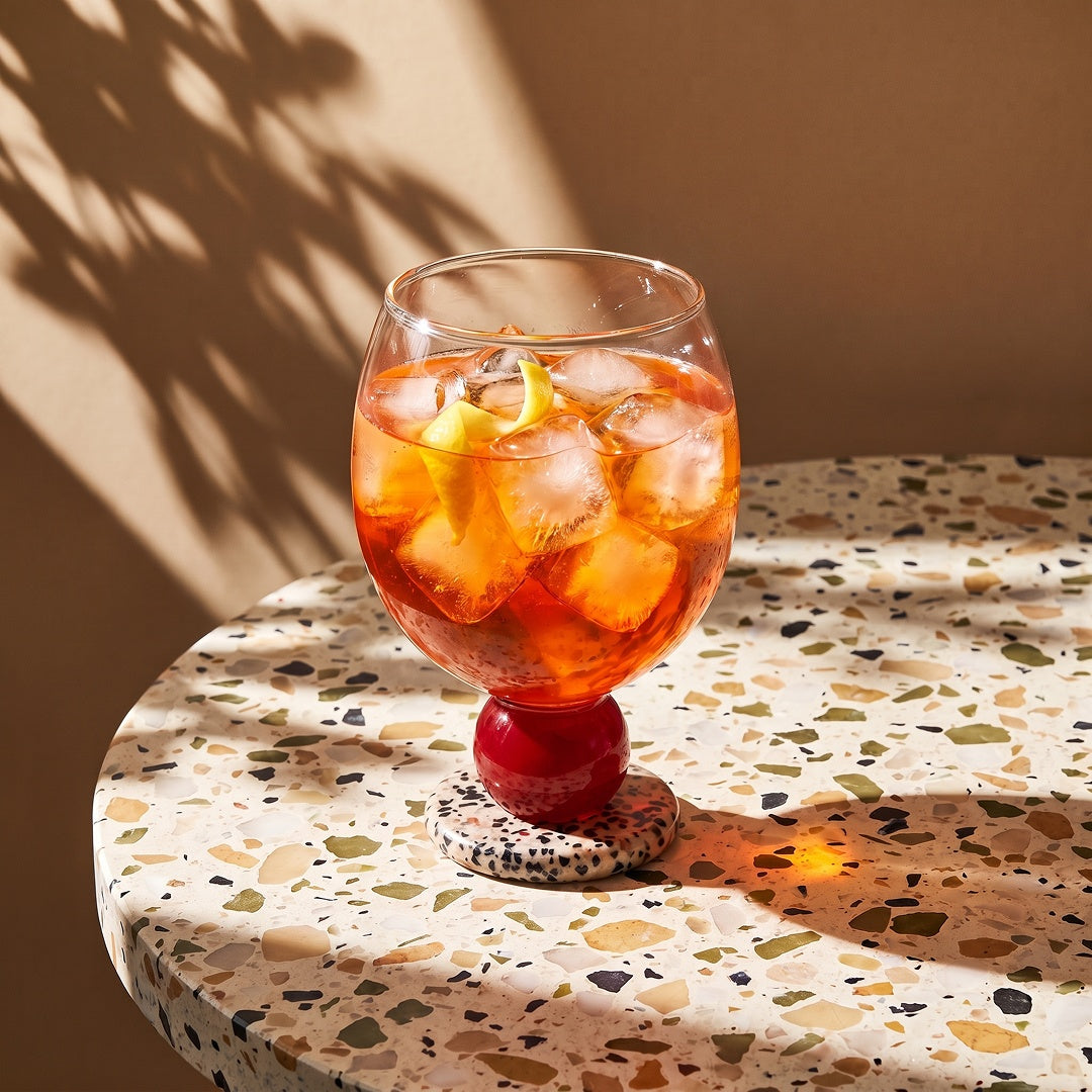 Stone base glass with an iced drink on a terrazzo table