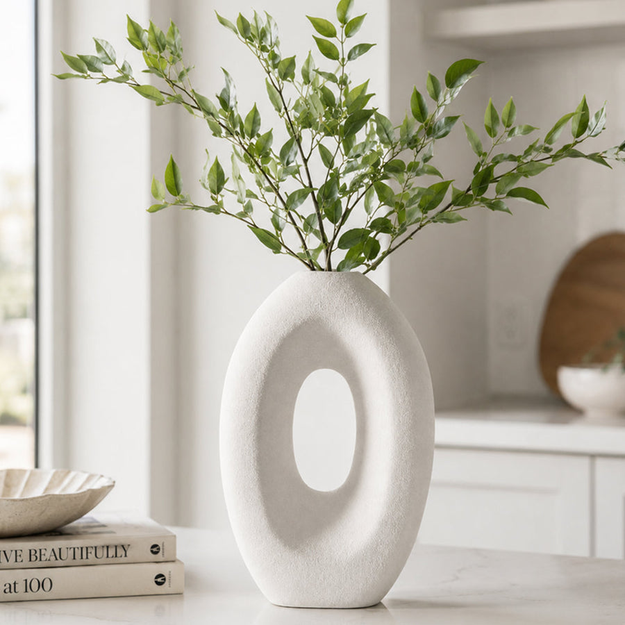 Handmade ceramic sculpture vase with a hollow center on a shelf