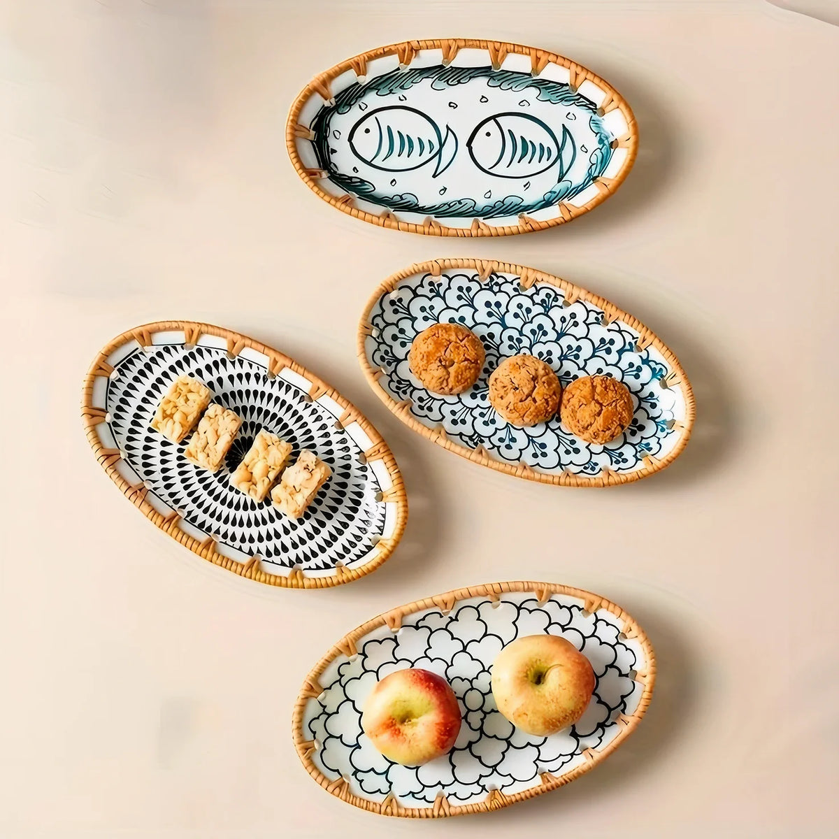 Four oval serving plates with fruit and snacks on a white table