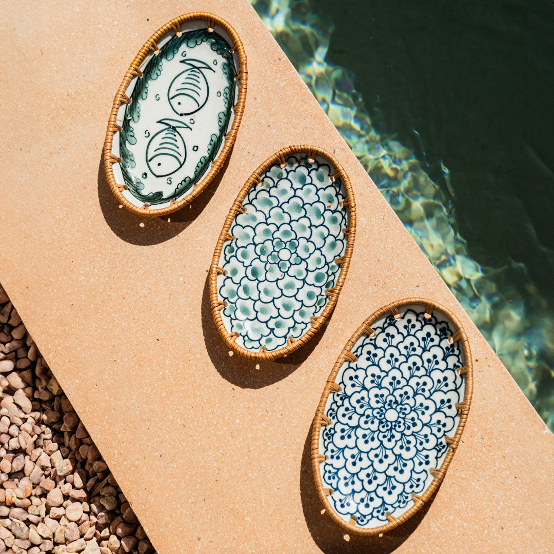 Three oval serving plates on a wooden board next to a pool