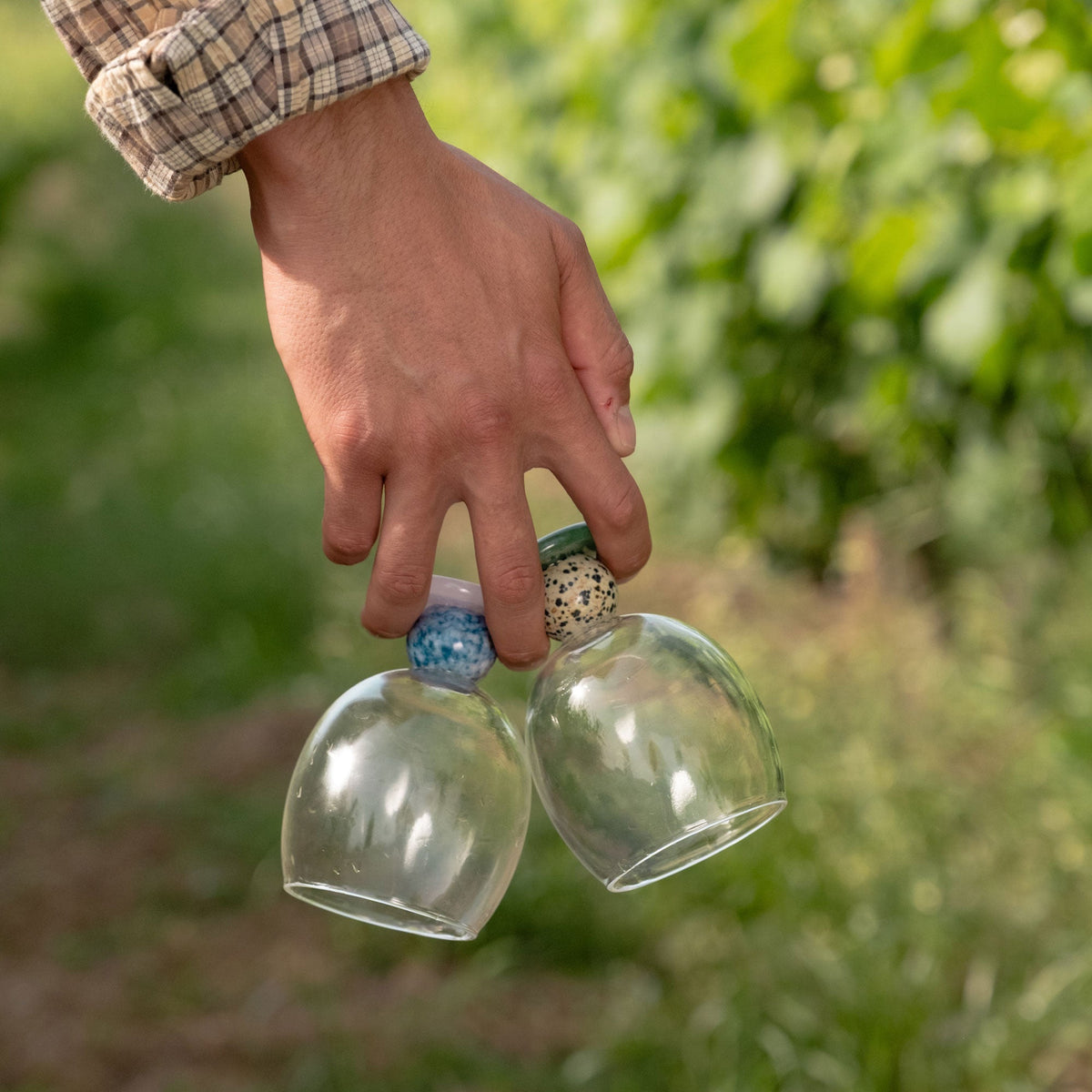 Hand carrying two stone base drinking glasses outdoors