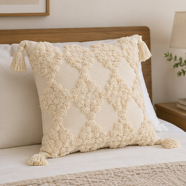 Beige square tufted throw pillow with tassel accents on a sofa