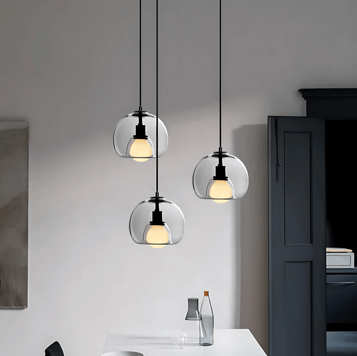 Three clear Clyde glass pendant lights in a white room
