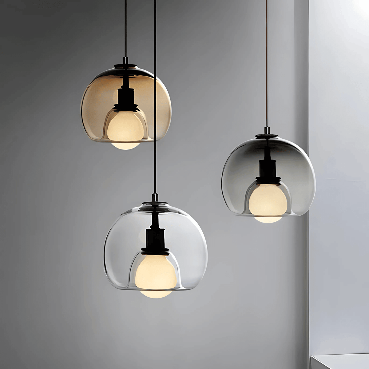 Three Clyde glass pendant lights in amber, smoke gray and clear