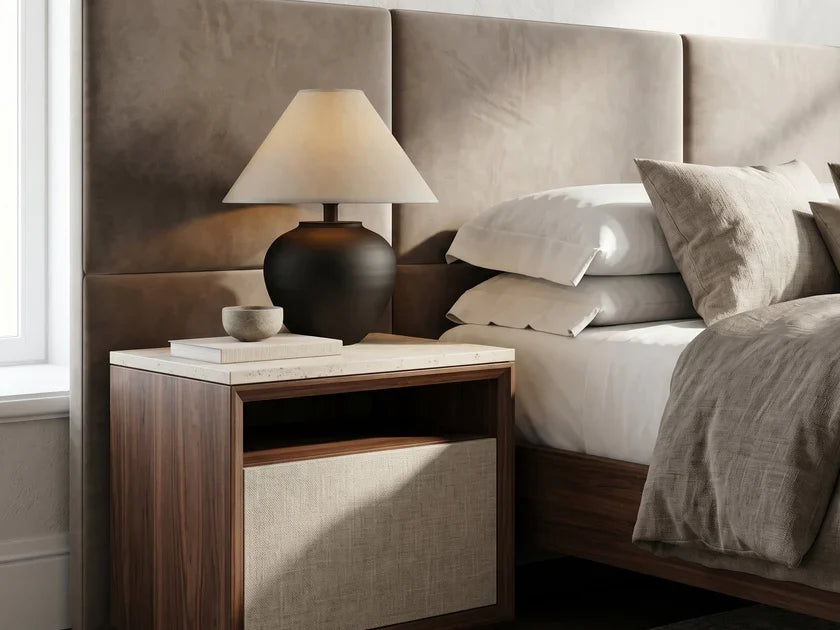 Matte black ceramic table lamp with a cream linen shade on a nightstand beside a bed