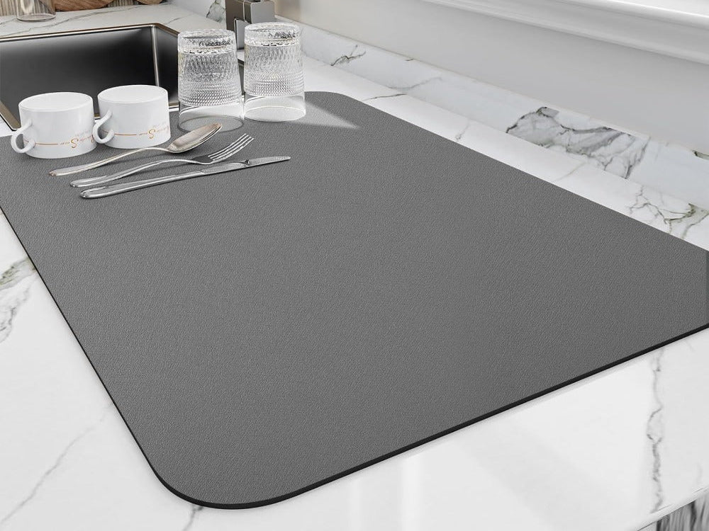 Gray dish drying mat with cups, glasses and cutlery drying on a marble counter