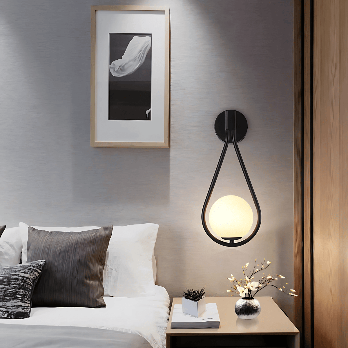 Black teardrop wall sconce above a nightstand beside the bed