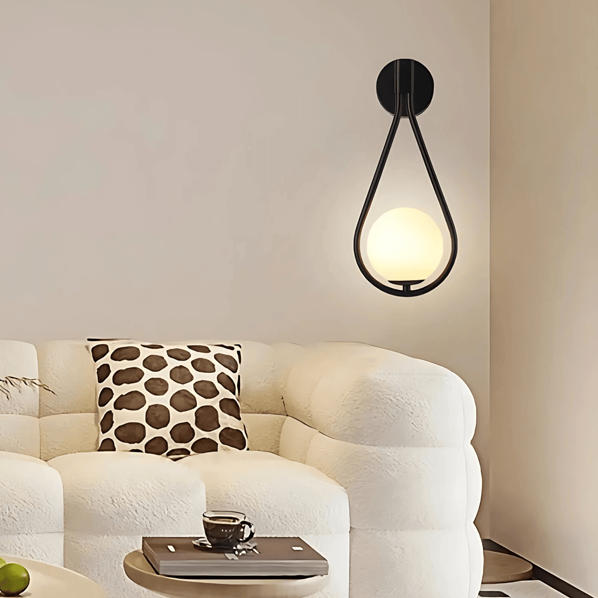 Black teardrop wall sconce above a white boucle sofa