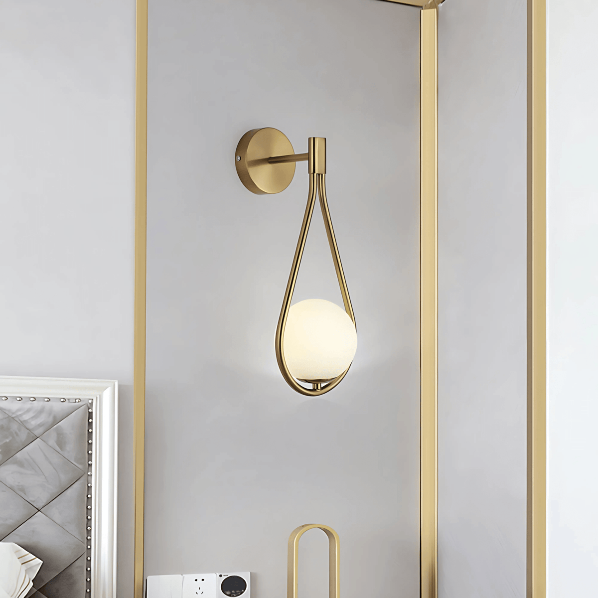 Brass teardrop wall sconce on a light bedroom wall