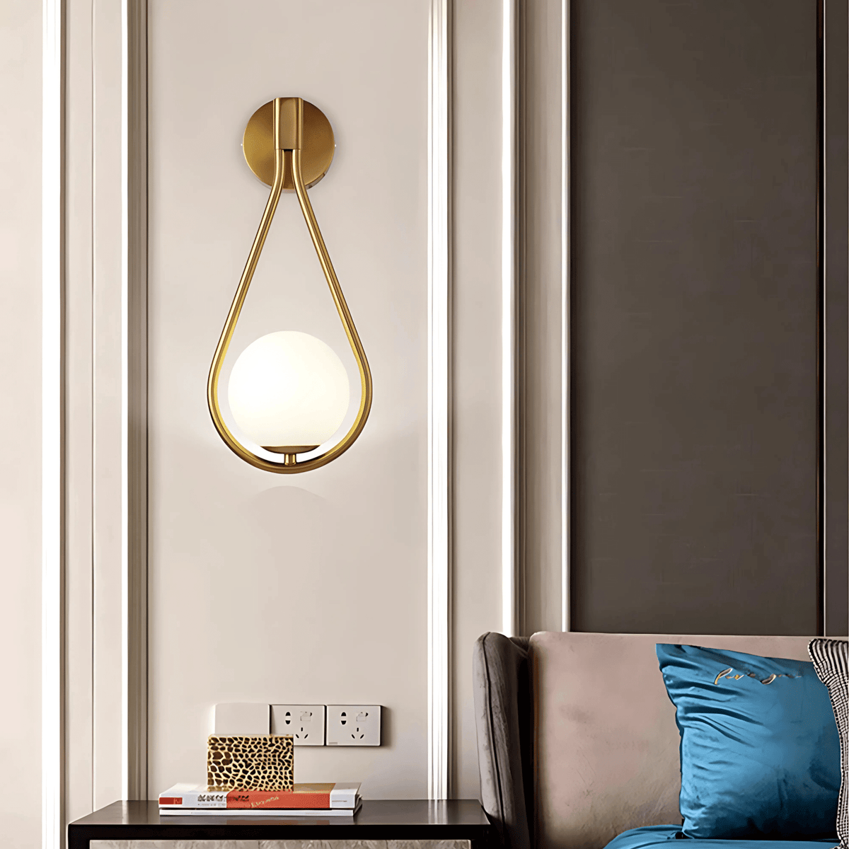 Brass teardrop wall sconce over a side table next to a sofa