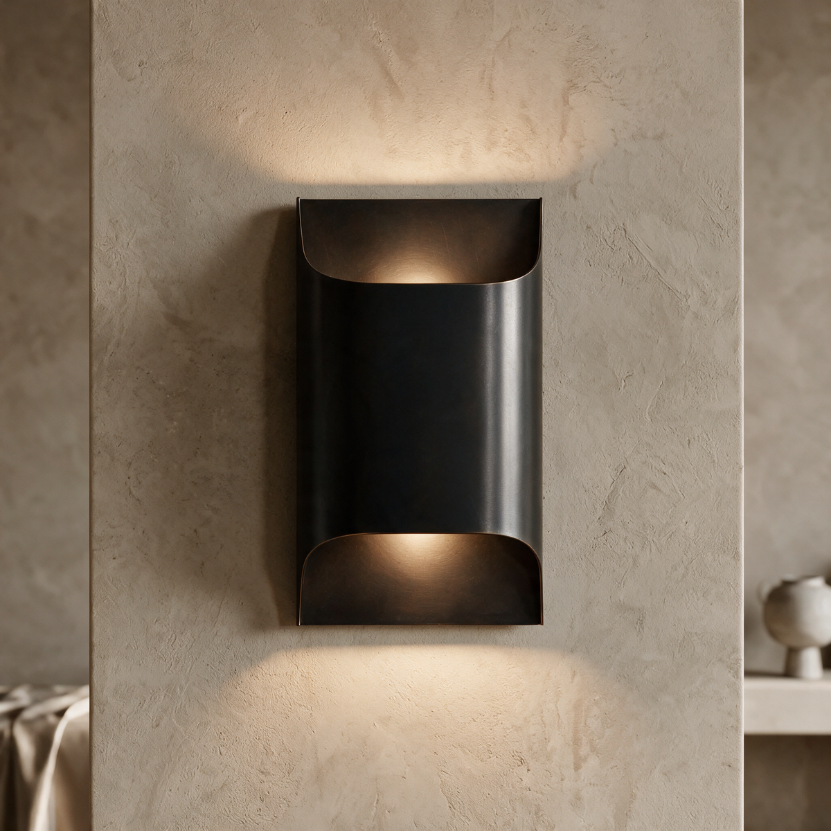 Tall matte black wall sconce lit on a textured plaster wall