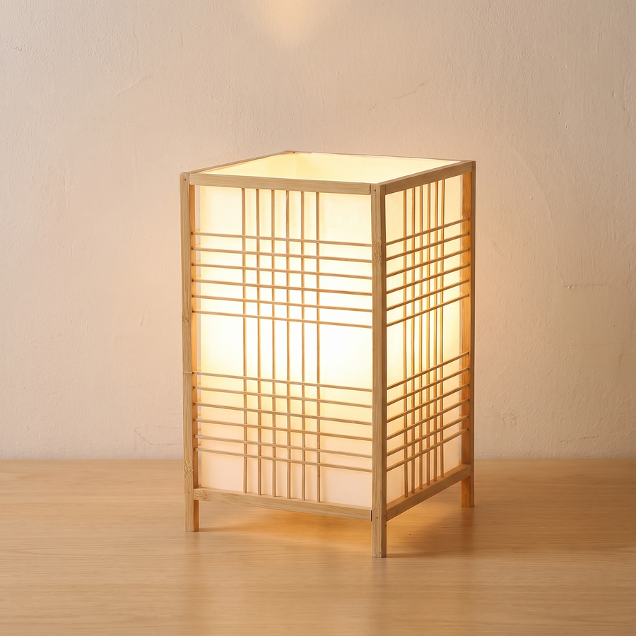 Lit bamboo grid lantern table lamp on a light wooden table