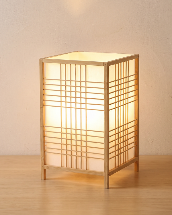 Lit bamboo grid lantern table lamp on a light wooden table