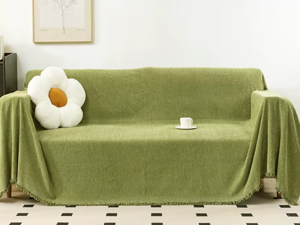 Green chenille couch cover draped over a sofa in a bright living room