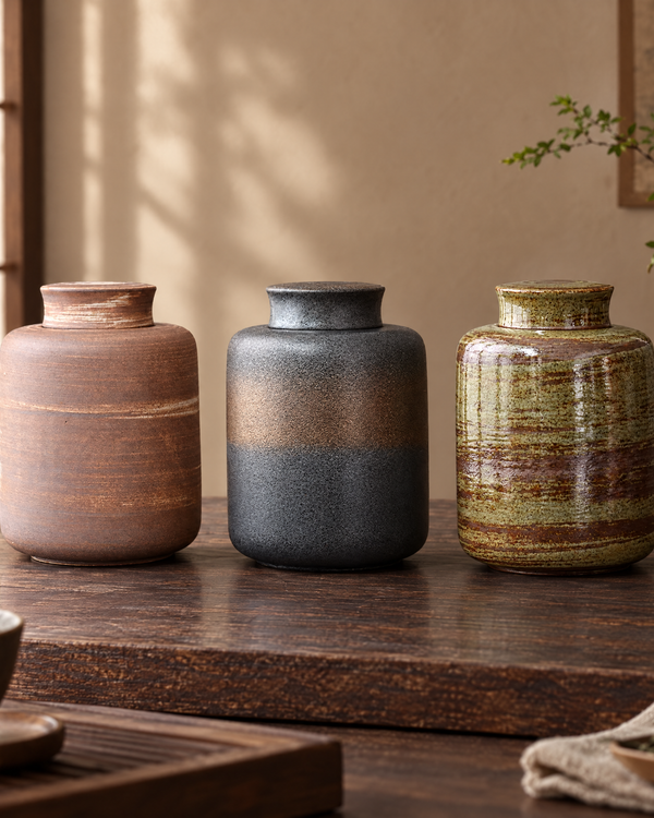 Three handmade ceramic storage jars in pale clay, iron and moss glaze on a shelf