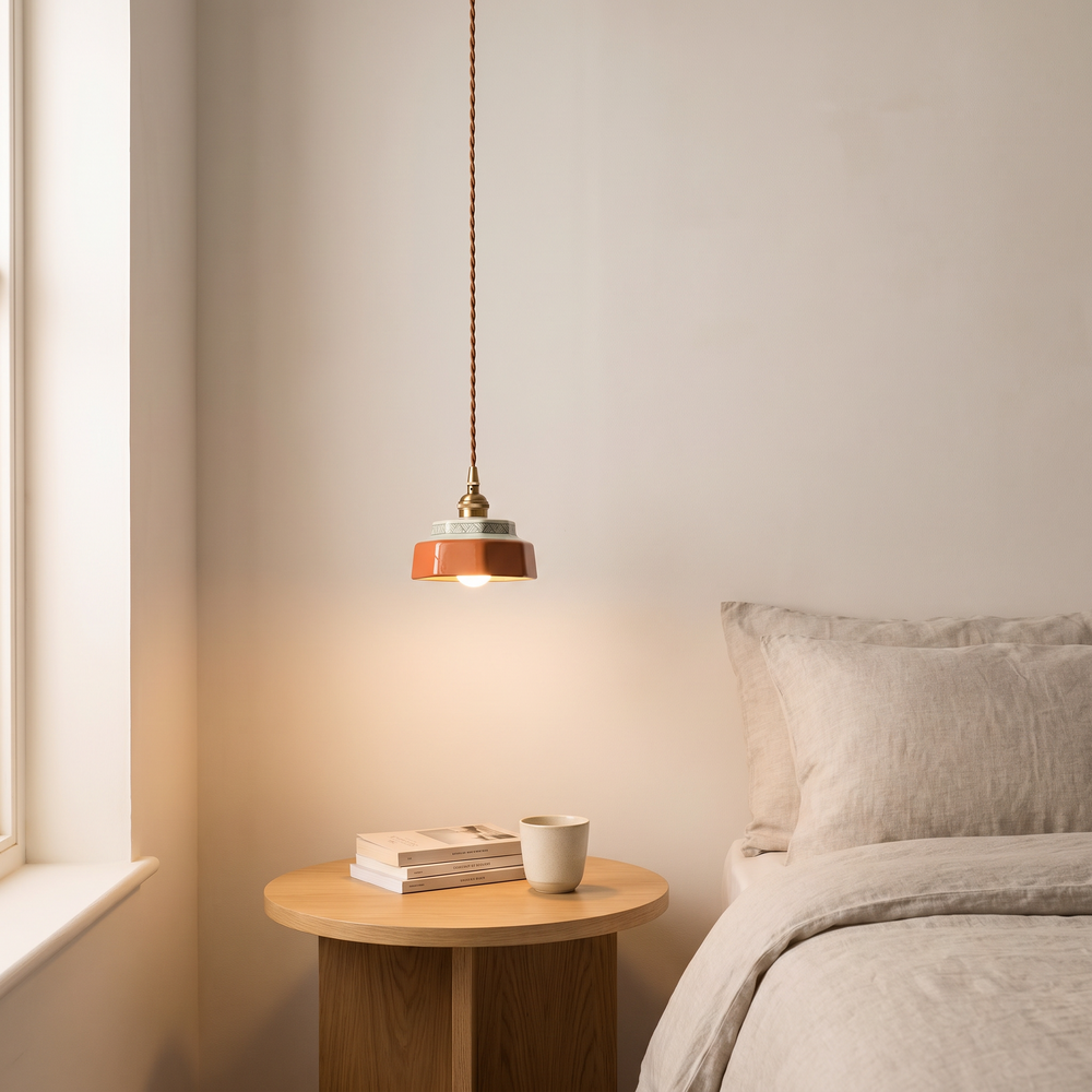 Red hand-painted ceramic mini pendant light hanging over a bedside table