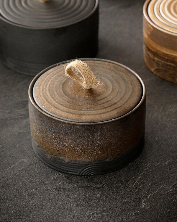 Handmade Japanese ceramic storage jar with hemp rope handle on a light styled tabletop