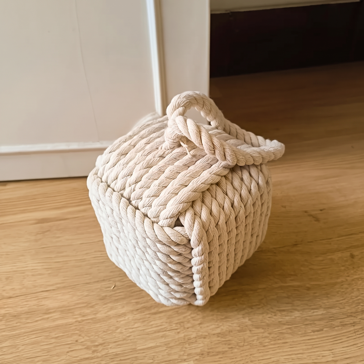 White rope cube door stop with a carry loop on a wood floor