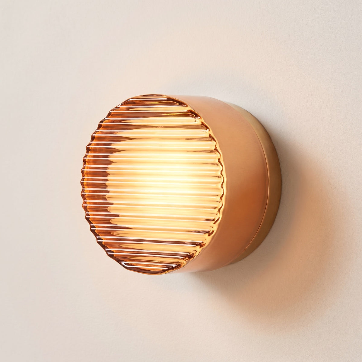 Hera glass wall sconce in Orange, Style A, ribbed amber glass on a plaster wall