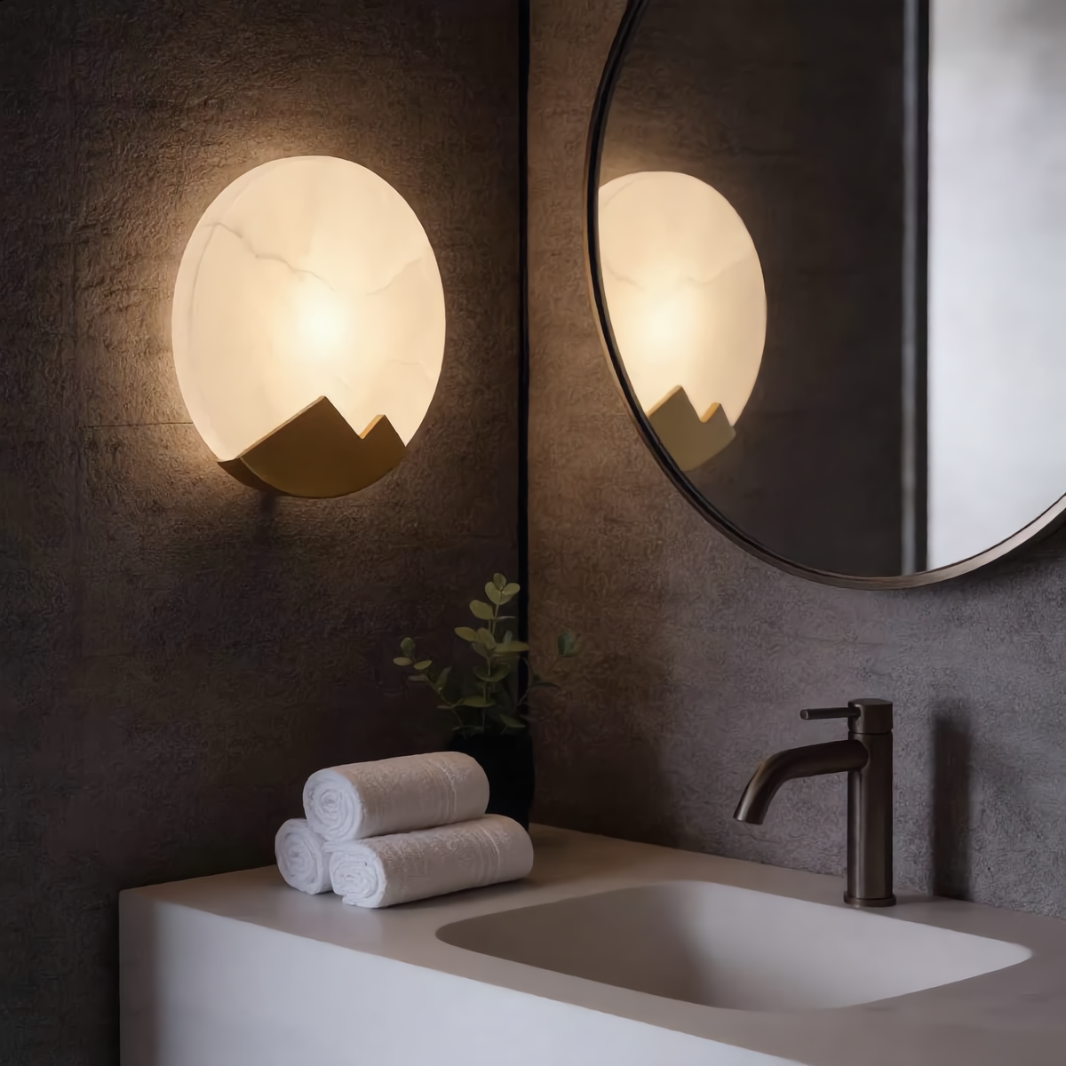 Alabaster wall sconce glowing warm white, its round marble disc lit from within